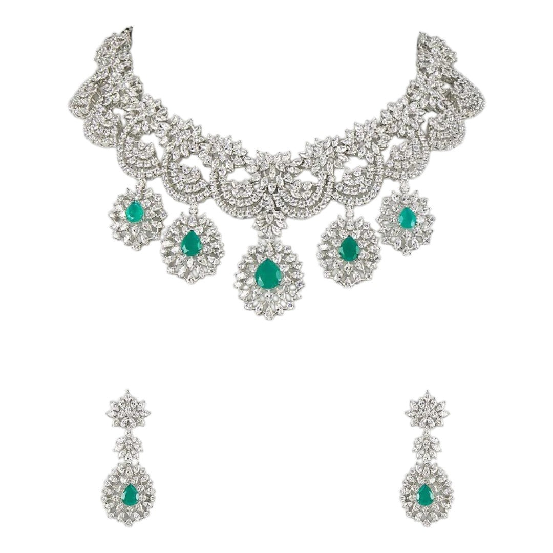 "Silver rhodium-plated bridal necklace set with white American diamonds and green emerald drop stones, paired with matching floral drop earrings"