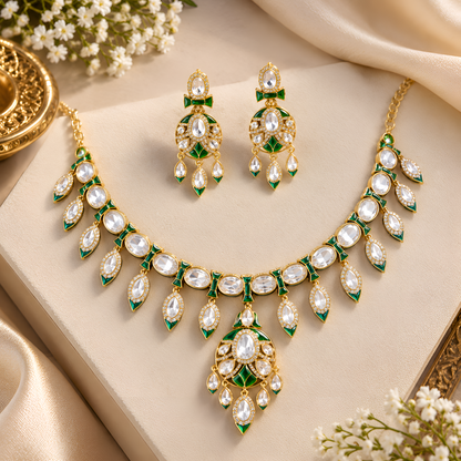 Gold-tone green meenakari kundan necklace set with round centre pendant, leaf-shaped drops and matching drop earrings on a grey display bust
