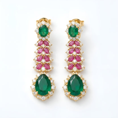 Gold-tone American diamond long drop earrings with emerald-green oval tops, ruby-pink marquise leaf rows and large emerald-green pear drops on dark green velvet