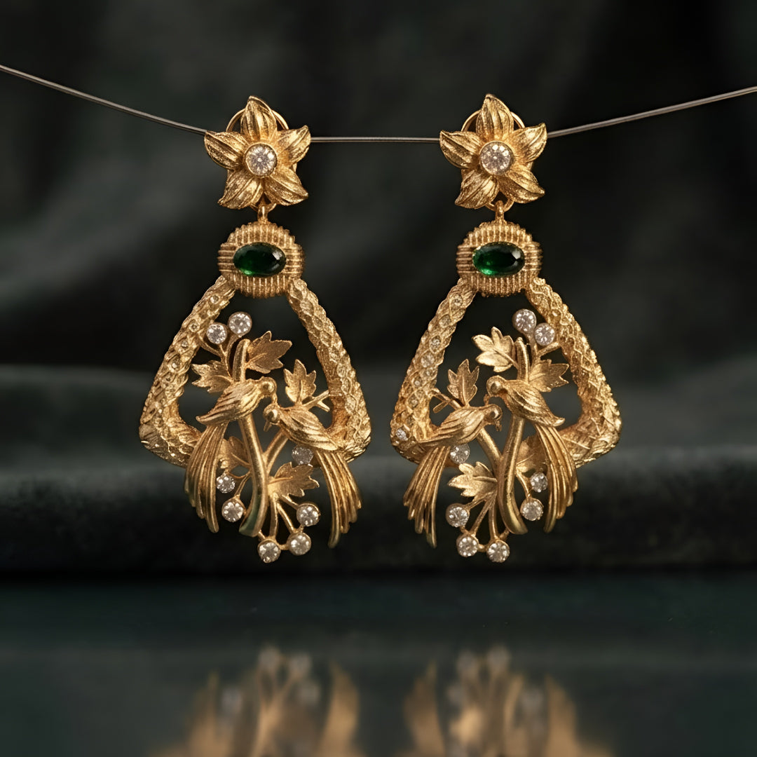 "Antique matte gold bird motif earrings with emerald green stone and CZ accents, floral stud design on dark background"