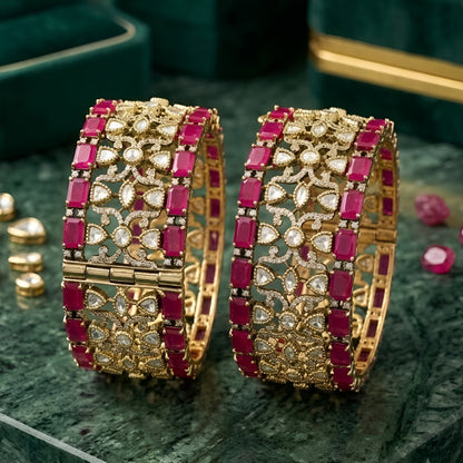 Pair of antique gold-finish wide kada bangles with ruby-pink rectangular stones, polki-style clear stones, and Victorian-style American diamond scrollwork