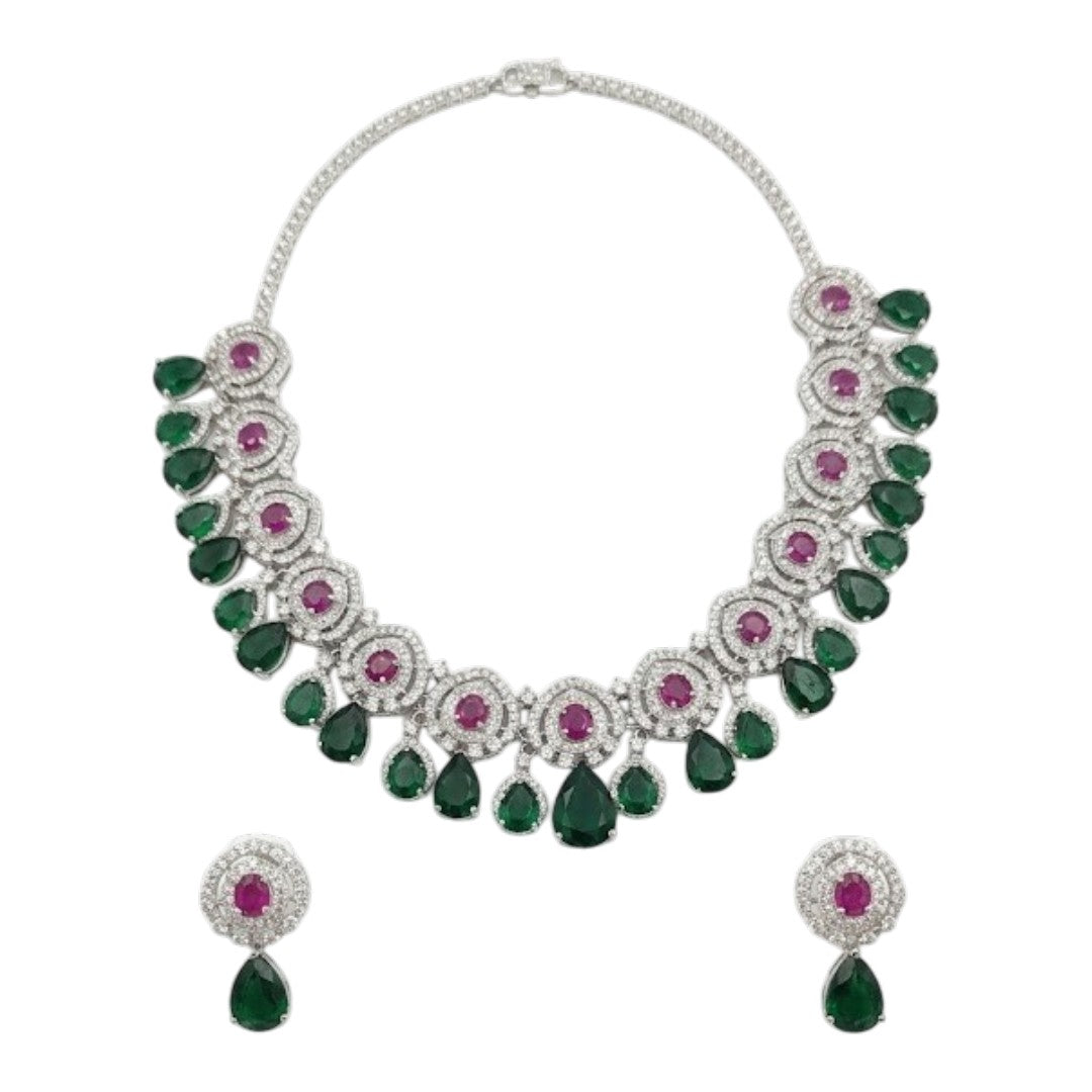 Luxury emerald green and ruby stone diamond-finish necklace set with matching earrings on white background.
