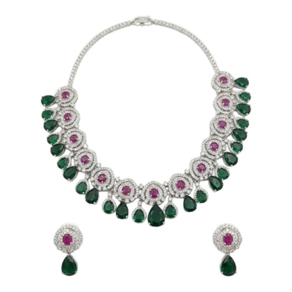 Luxury emerald green and ruby stone diamond-finish necklace set with matching earrings on white background.
