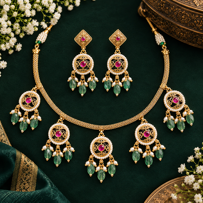 Antique gold plated choker necklace set with ruby pink medallions, mint green bead and pearl drops and matching earrings on a blue bust