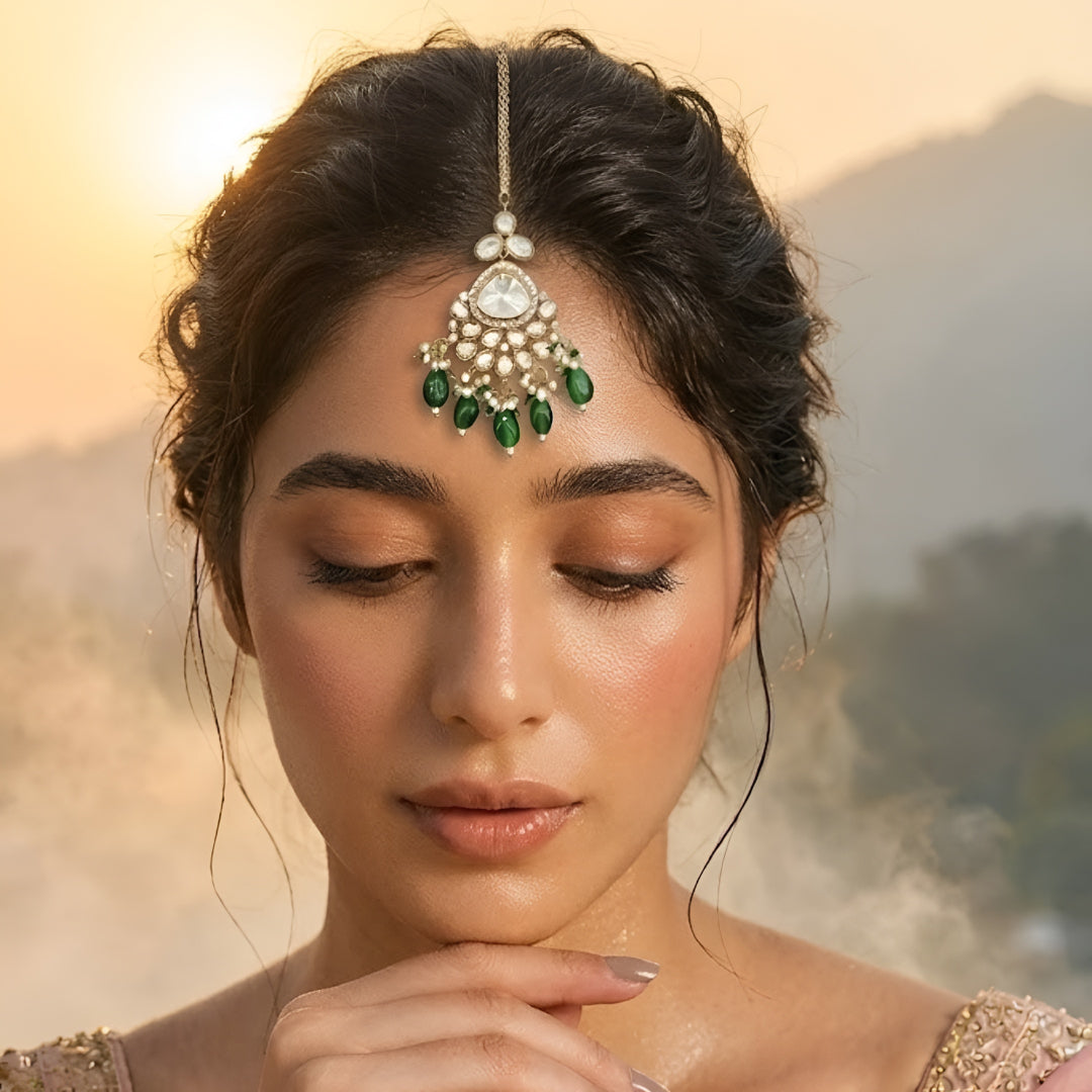 Gold plated Kundan maang tikka with white Polki stones, green bead drops, and pearl detailing for bridal wedding and festive wear.