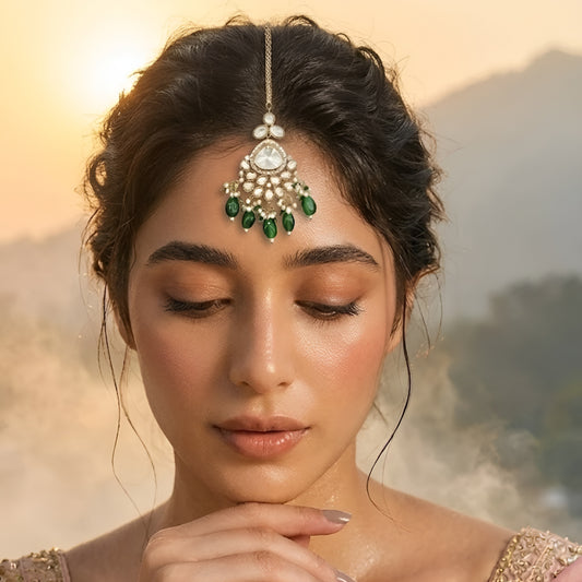 Gold plated Kundan maang tikka with white Polki stones, green bead drops, and pearl detailing for bridal wedding and festive wear.