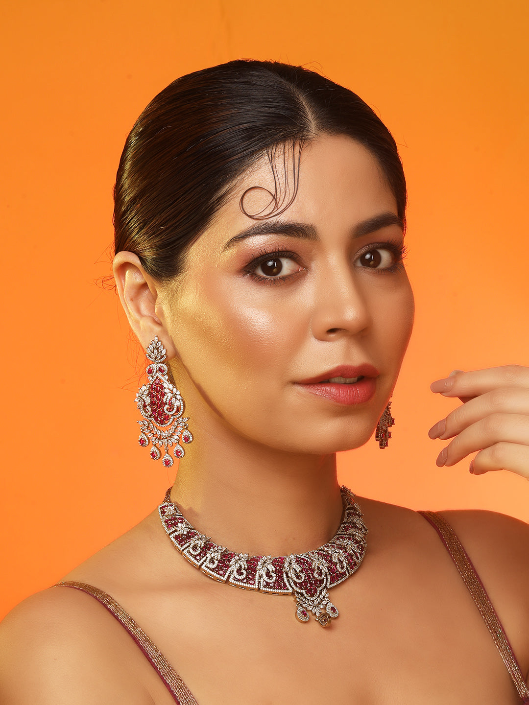 Gold-tone statement necklace set with pink ruby-style stones and clear crystals in an intricate floral design, paired with matching chandelier earrings featuring drop accents.