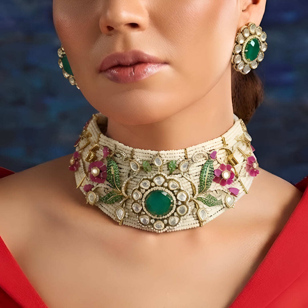 Designer gold-plated Kundan pearl choker necklace set with green centerpiece, floral pink stones, and matching stud earrings for women.