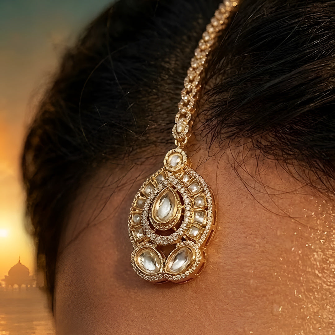 Elegant gold-plated Kundan pearl maang tikka with teardrop stone and crystal detailing for bridal and festive wear.