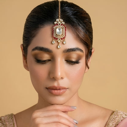 Gold-plated Kundan Maang Tikka featuring a rectangular white crystal centerpiece, ruby red stones, and elegant teardrop danglers for bridal and festive wear.