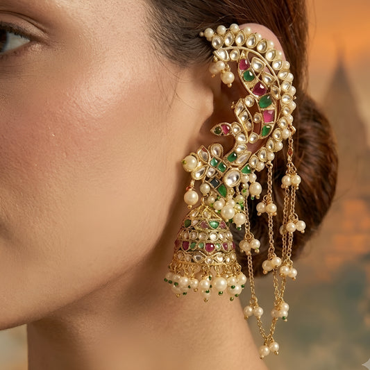 Elegant gold-tone ear cuff and jhumka earrings featuring a crescent-shaped ear climber adorned with sparkling white stones and pink and green gemstone accents. Each earring is paired with a floral motif, a traditional dome-shaped jhumka embellished with multicolored stones and pearl drops, and delicate cascading chains that connect to a hair hook, accented with tiny pearl clusters.
