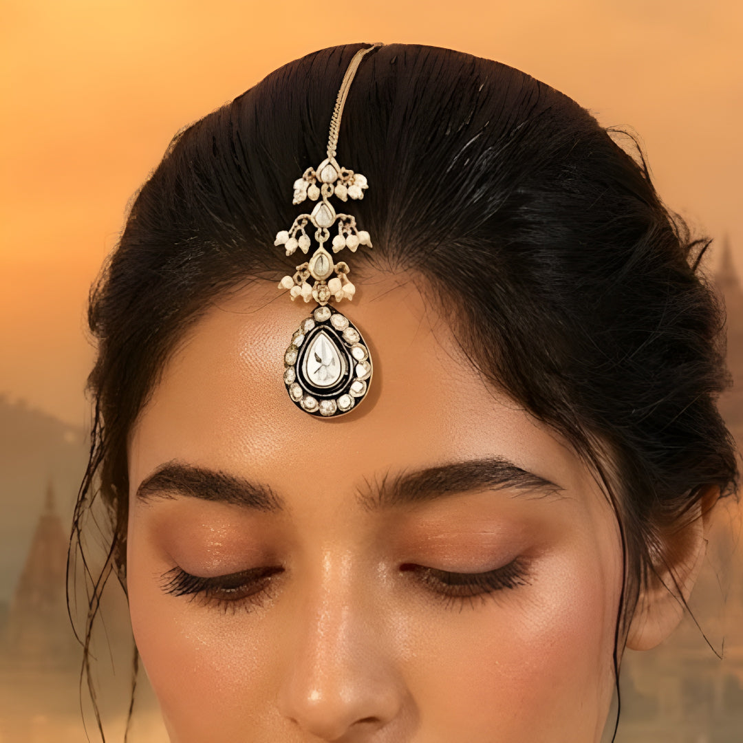 Gold-toned black enamel Kundan teardrop maang tikka with faux pearl bead clusters for bridal, wedding, and festive wear.