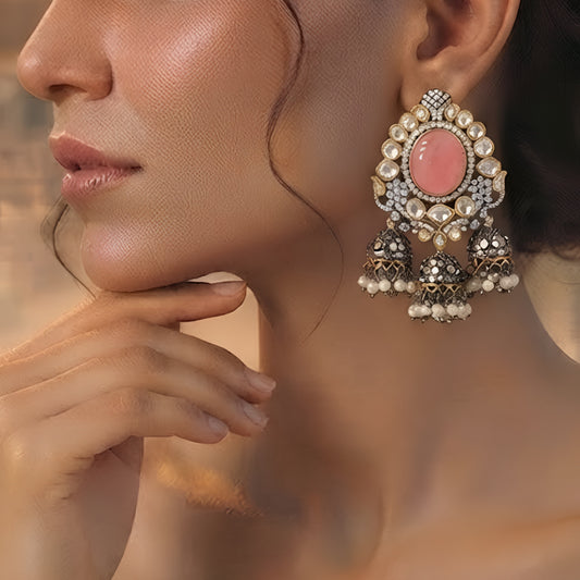 Pink Kundan jhumka earrings with antique gold finish, oval pink stone, sparkling Kundan crystals, and pearl tassel drops for bridal and festive wear.