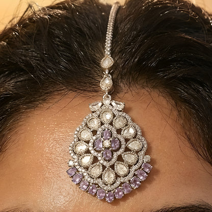 Silver-tone Kundan maang tikka with white stones and purple crystal accents, perfect for bridal, wedding, and festive wear.