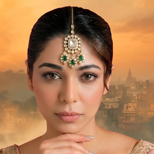 Gold-plated Kundan Maang Tikka featuring a square white center stone with emerald green teardrop stones and intricate floral detailing for bridal and festive wear.