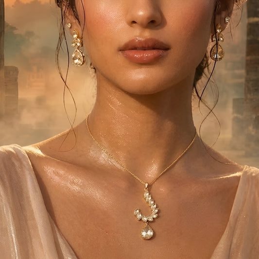Gold-toned leaf design pendant necklace set with teardrop crystal pendant and matching drop earrings on a white background.