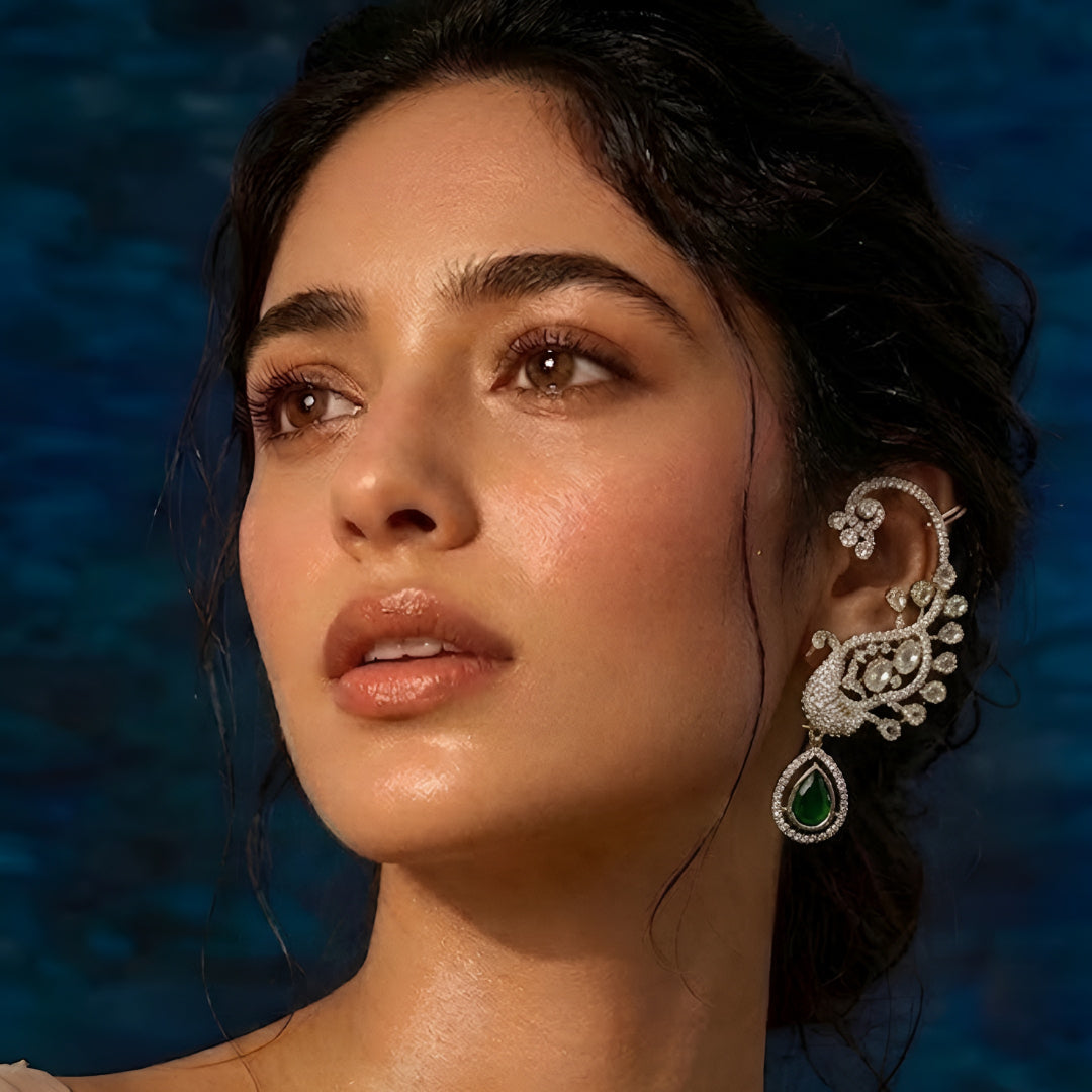 Luxury gold-plated peacock ear cuff earrings with Kundan Polki stones, sparkling CZ detailing, and emerald green teardrop crystal pendant for bridal and festive wear.
