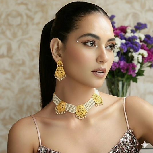 Temple-style gold plated necklace set with long matching earrings on red display stand