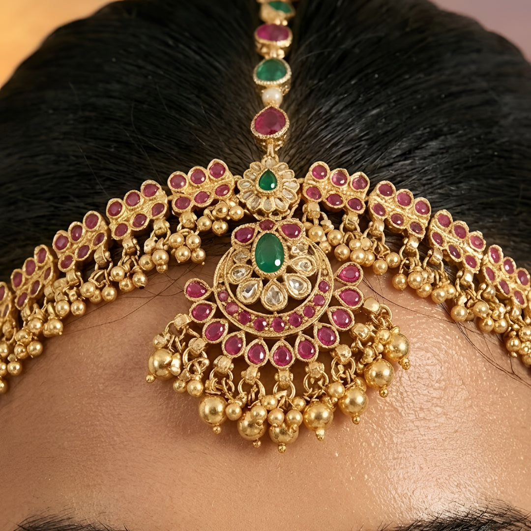 Traditional gold-plated Matha Patti with pink and green Kemp stones and matching maang tikka, perfect for bridal and festive wear.