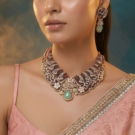 Designer ruby red kundan choker necklace set with sparkling crystal detailing, mint green teardrop gemstone centerpiece, and matching earrings for bridal and festive occasions.