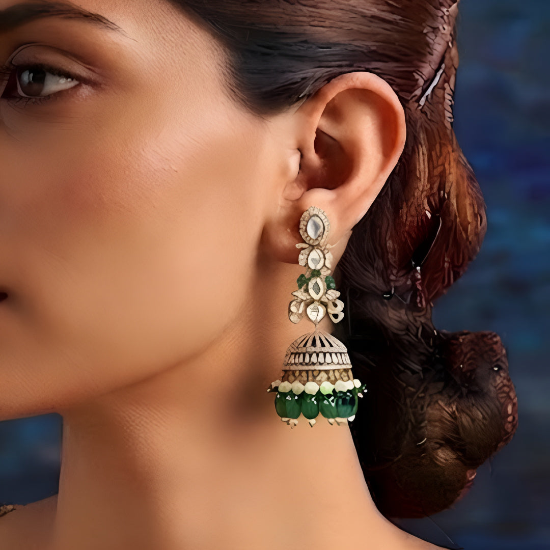 Luxury gold-plated Kundan jhumka earrings with sparkling CZ stones, emerald green bead drops, and pearl accents for women.