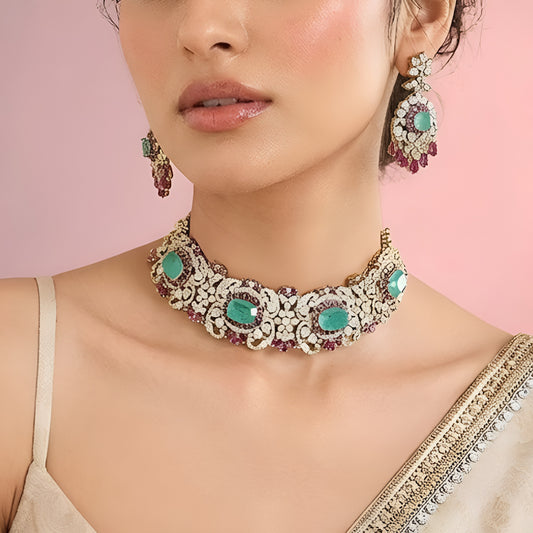 Luxury emerald green kundan choker necklace set with sparkling polki stones, ruby pink accents, and matching chandelier earrings for bridal and wedding wear.