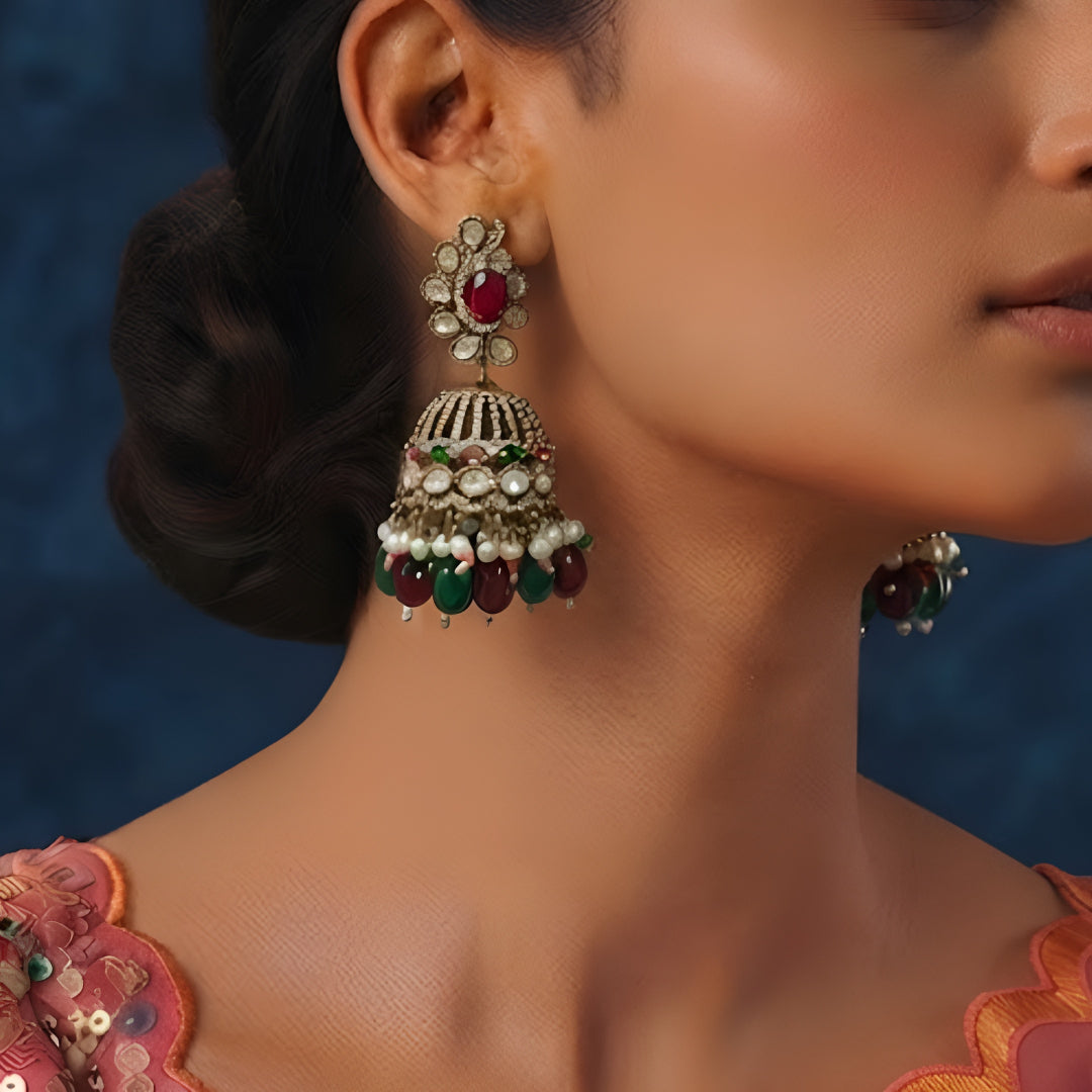 Antique gold Kundan jhumka earrings with ruby center stones, green bead drops, pearl accents, and traditional bridal design for women.
