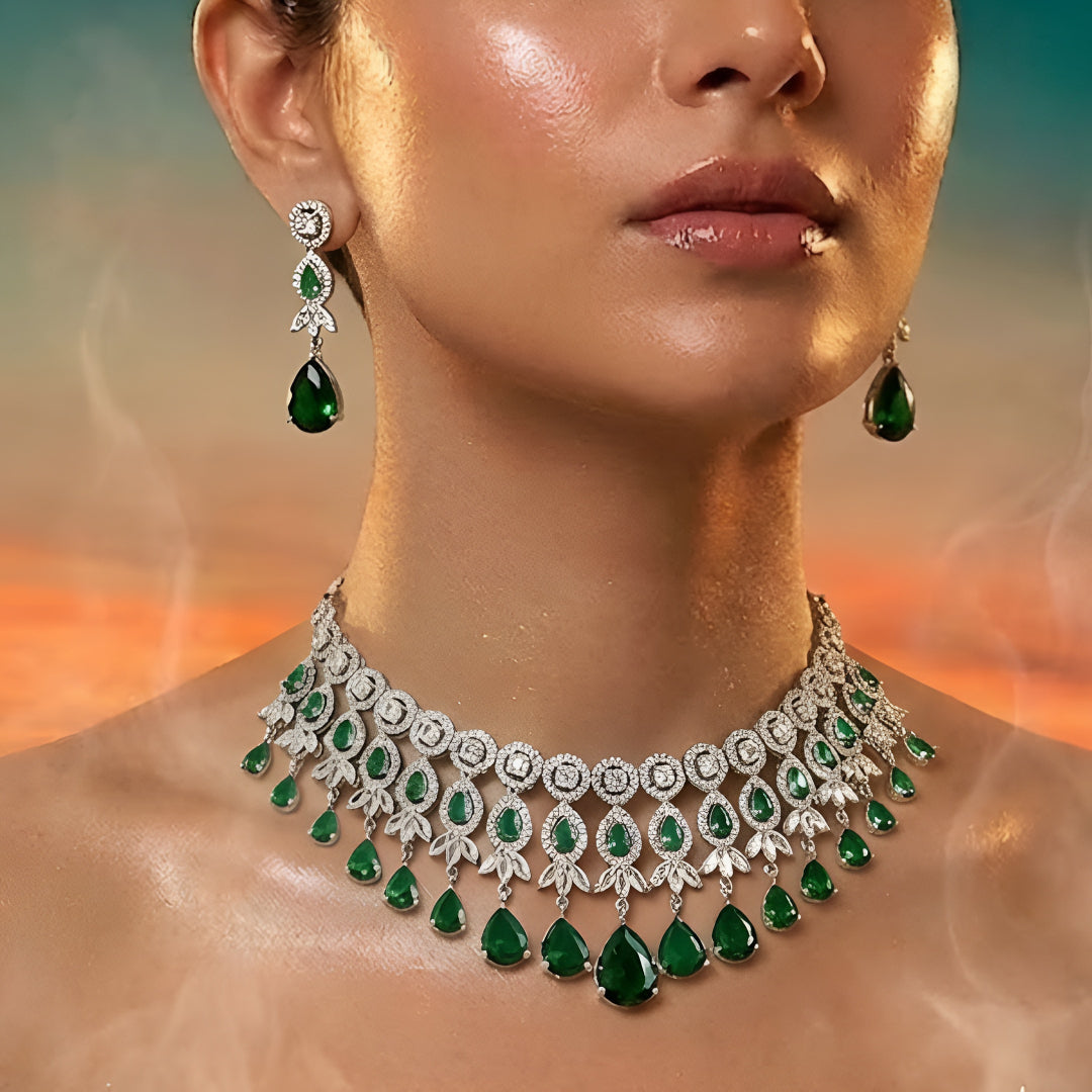 Silver-tone choker necklace and earrings set featuring sparkling clear crystals and emerald green teardrop stones in an elegant bridal jewelry design.