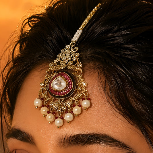Traditional gold-plated Kundan maang tikka with pink teardrop stone, white pearl drops and beaded chain for bridal and festive wear.
