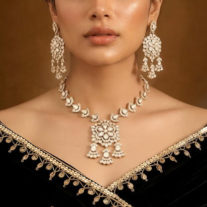 Gold-tone Kundan floral necklace set featuring a statement pendant with dangling accents and matching drop earrings on a white background.