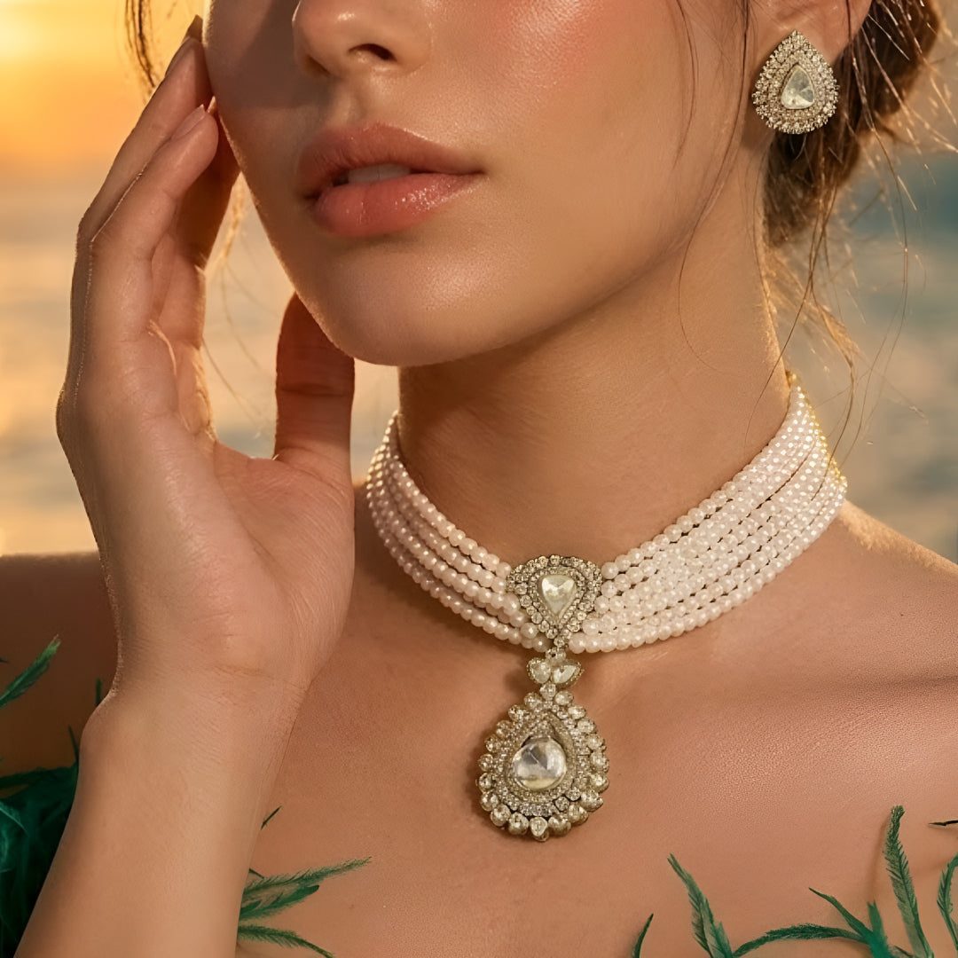 Multi-strand pearl choker necklace featuring a teardrop Kundan pendant with matching stud earrings on a white background.