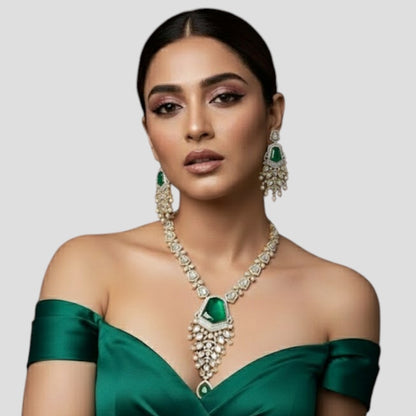 "Long gold-finish necklace set with emerald green stones, white American Diamond detailing, cascading pearl-style drops and matching long earrings displayed on a light background."