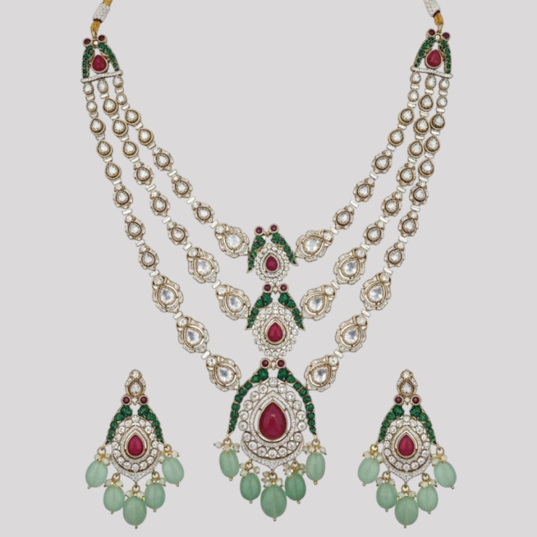 "Triple-layer gold-finish necklace set with ruby stones, green accents, AD detailing, pastel green bead drops, and matching earrings displayed on a light background."