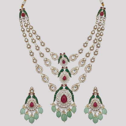 "Triple-layer gold-finish necklace set with ruby stones, green accents, AD detailing, pastel green bead drops, and matching earrings displayed on a light background."
