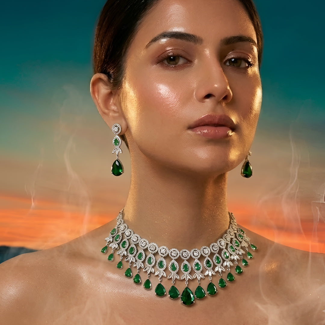Silver-tone choker necklace and earrings set featuring sparkling clear crystals and emerald green teardrop stones in an elegant bridal jewelry design.