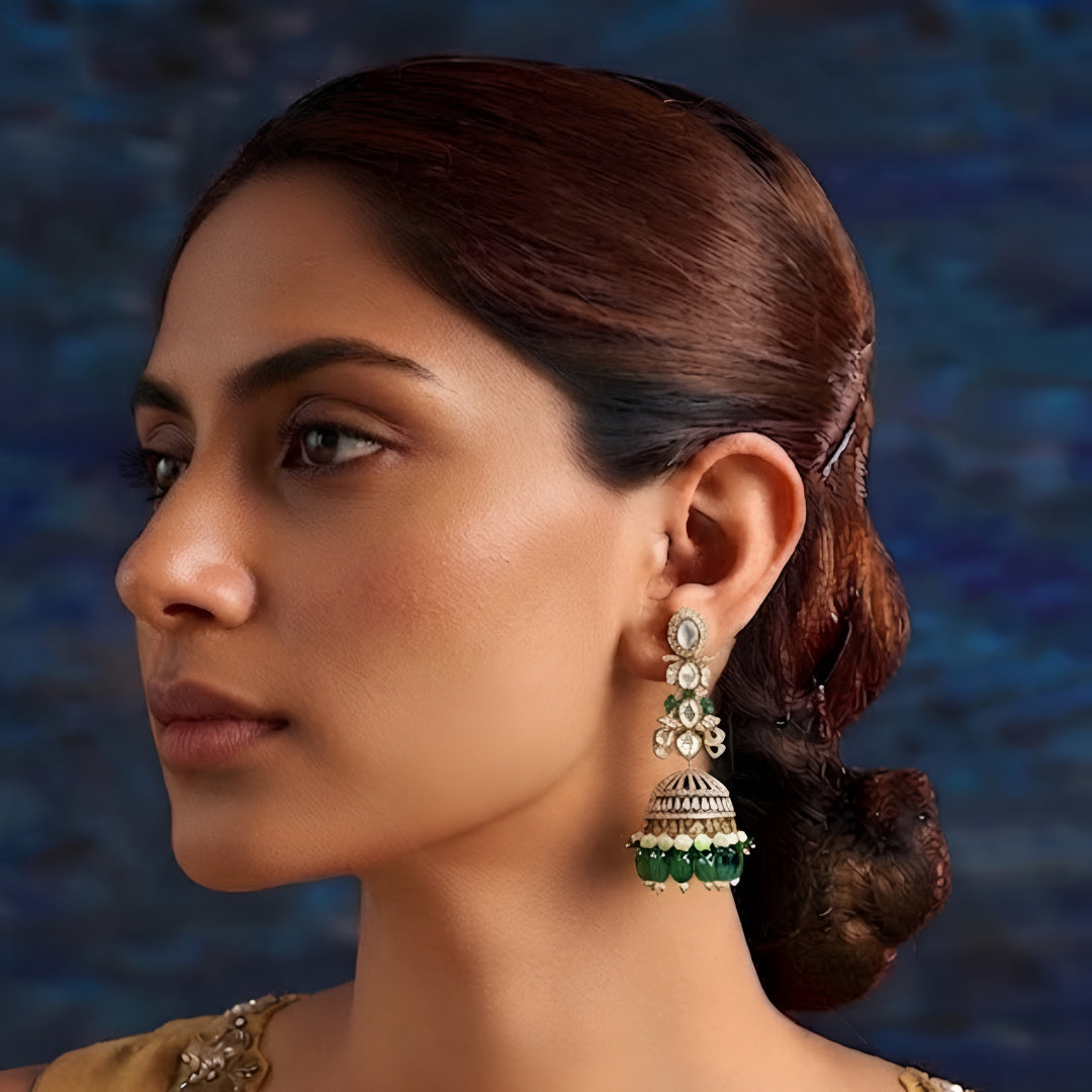 Luxury gold-plated Kundan jhumka earrings with sparkling CZ stones, emerald green bead drops, and pearl accents for women.