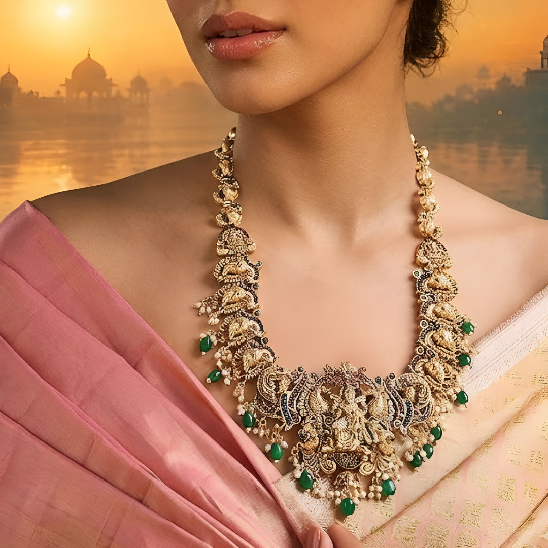 Antique gold Lakshmi temple necklace featuring traditional South Indian craftsmanship, ruby and green stone detailing, intricate deity motifs, and green bead drops for bridal and festive occasions.