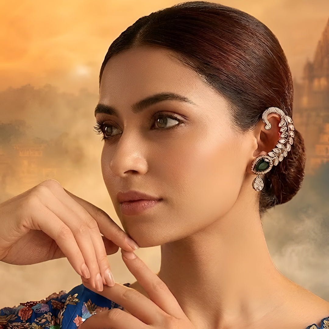 Gold-plated leaf design ear cuff earrings with emerald green teardrop stones and sparkling crystal embellishments for women.