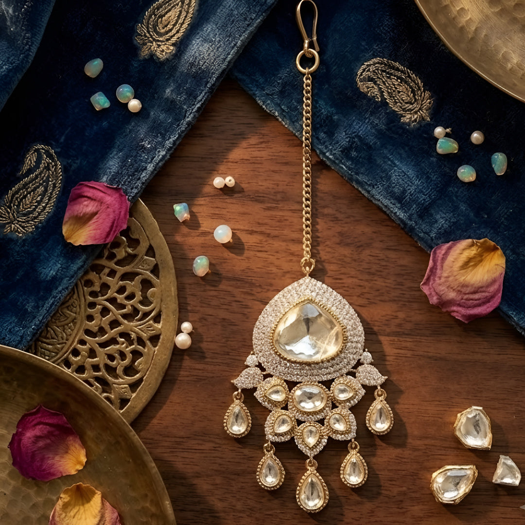 Elegant gold-plated Kundan maang tikka with white American diamond stones and pear-shaped crystal drops for bridal and wedding wear.