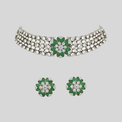 "Green floral American Diamond choker necklace set with matching stud earrings, featuring white AD stones, gold finish and adjustable yellow dori, displayed on a dark background."