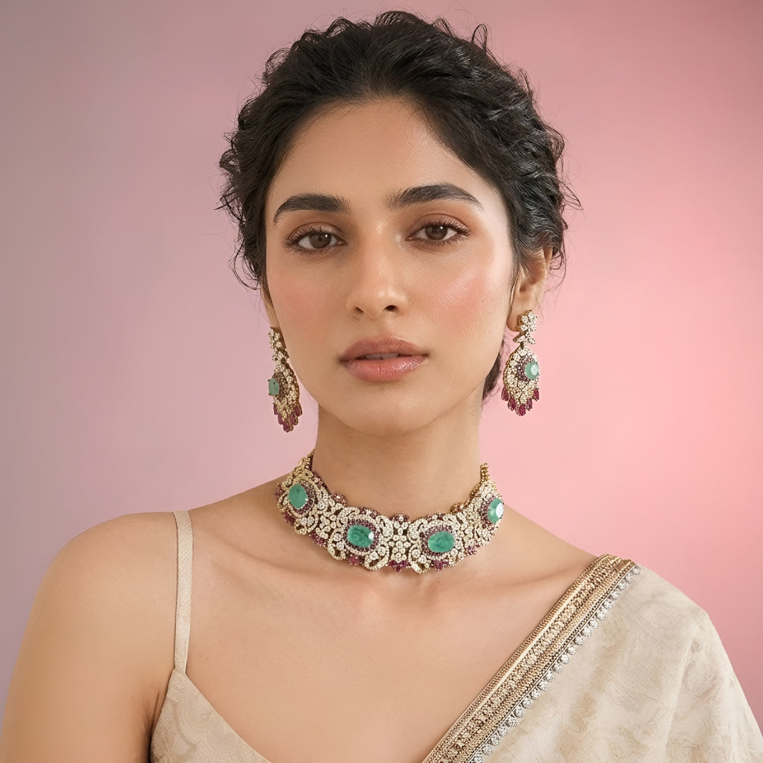 Luxury emerald green kundan choker necklace set with sparkling polki stones, ruby pink accents, and matching chandelier earrings for bridal and wedding wear.
