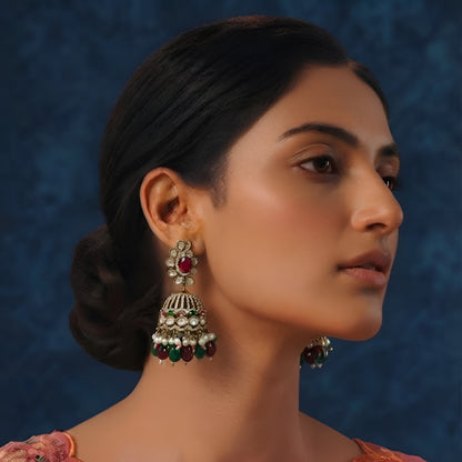 Antique gold Kundan jhumka earrings with ruby center stones, green bead drops, pearl accents, and traditional bridal design for women.