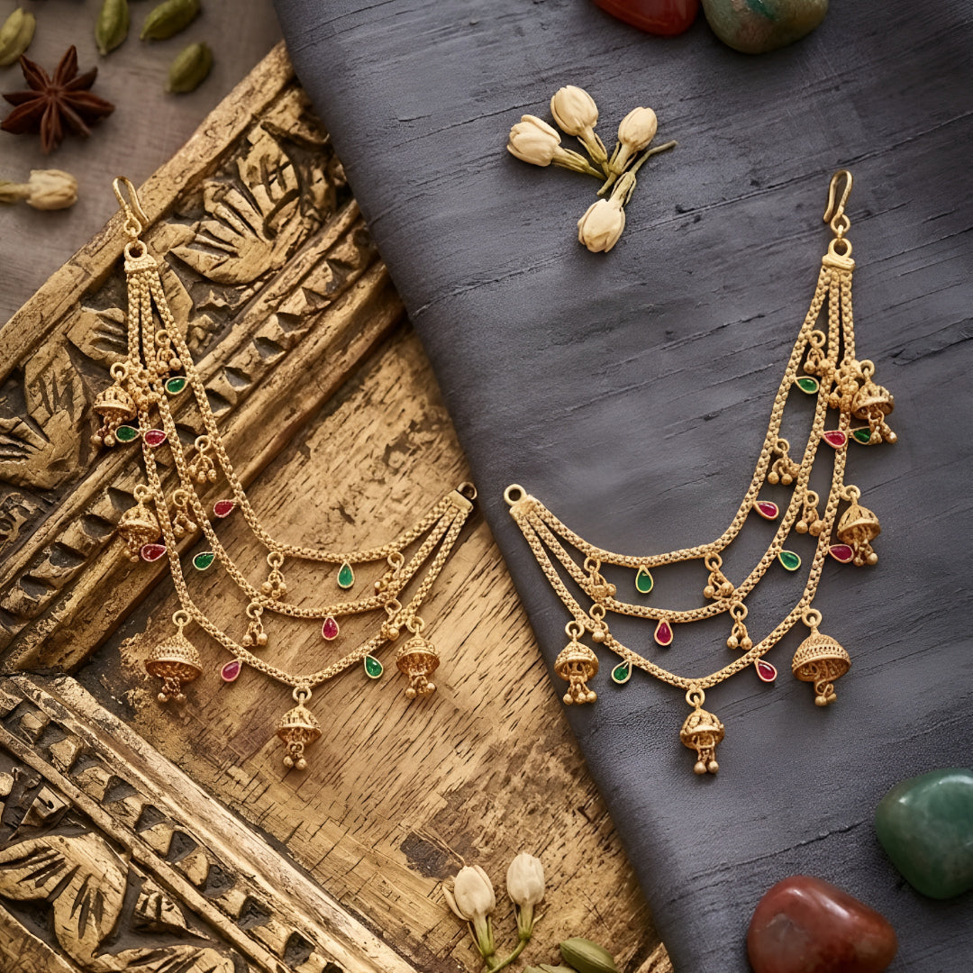 Traditional gold plated multilayer Kaan Chain with jhumka charms and red green stone detailing for women, perfect for bridal, wedding, festive, and ethnic wear.