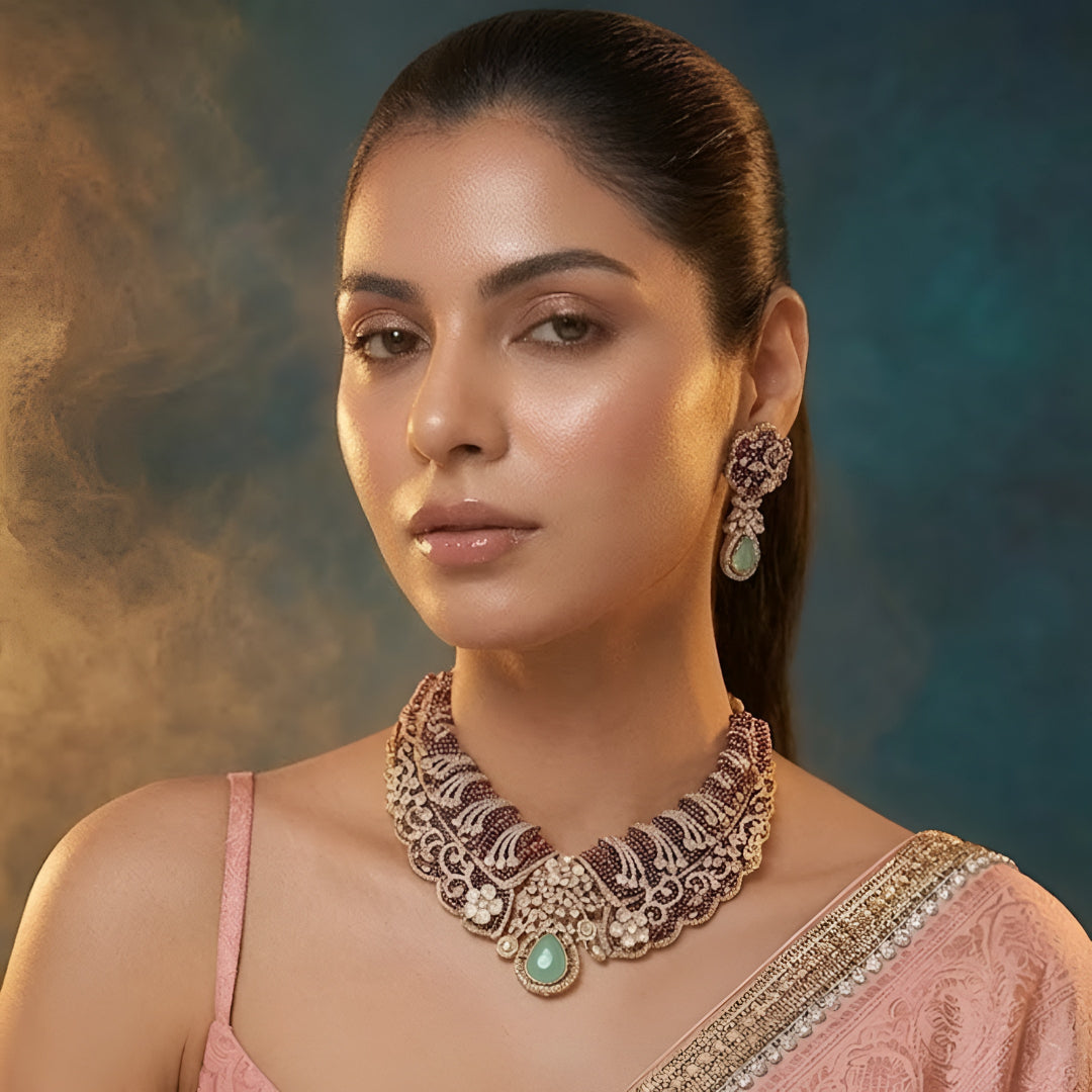 Designer ruby red kundan choker necklace set with sparkling crystal detailing, mint green teardrop gemstone centerpiece, and matching earrings for bridal and festive occasions.
