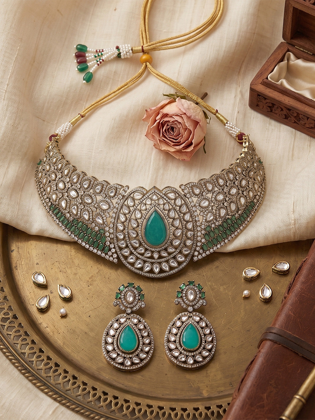 Gold-tone choker necklace set with intricate kundan-style detailing, highlighted by a large teardrop green stone centerpiece and matching drop earrings.