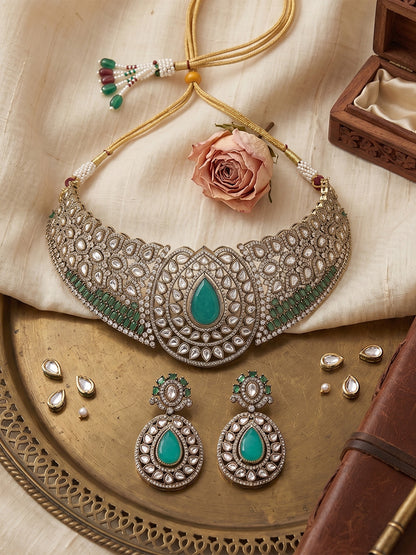 Gold-tone choker necklace set with intricate kundan-style detailing, highlighted by a large teardrop green stone centerpiece and matching drop earrings.
