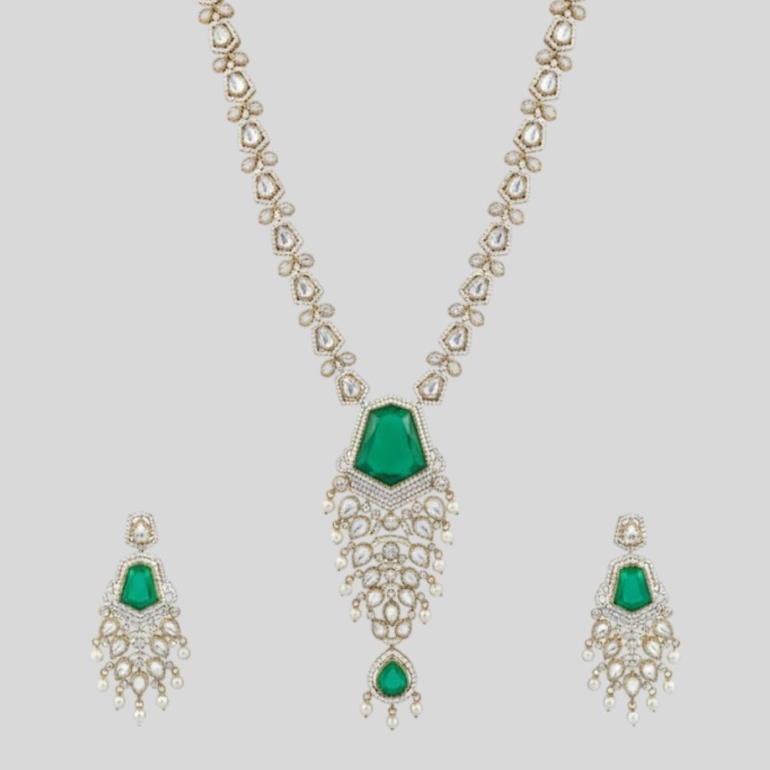"Long gold-finish necklace set with emerald green stones, white American Diamond detailing, cascading pearl-style drops and matching long earrings displayed on a light background."