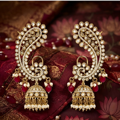 Luxury gold-plated Kundan Polki ear cuff jhumka earrings with ruby red bead drops, pearl tassels, and intricate floral detailing for bridal and festive wear.