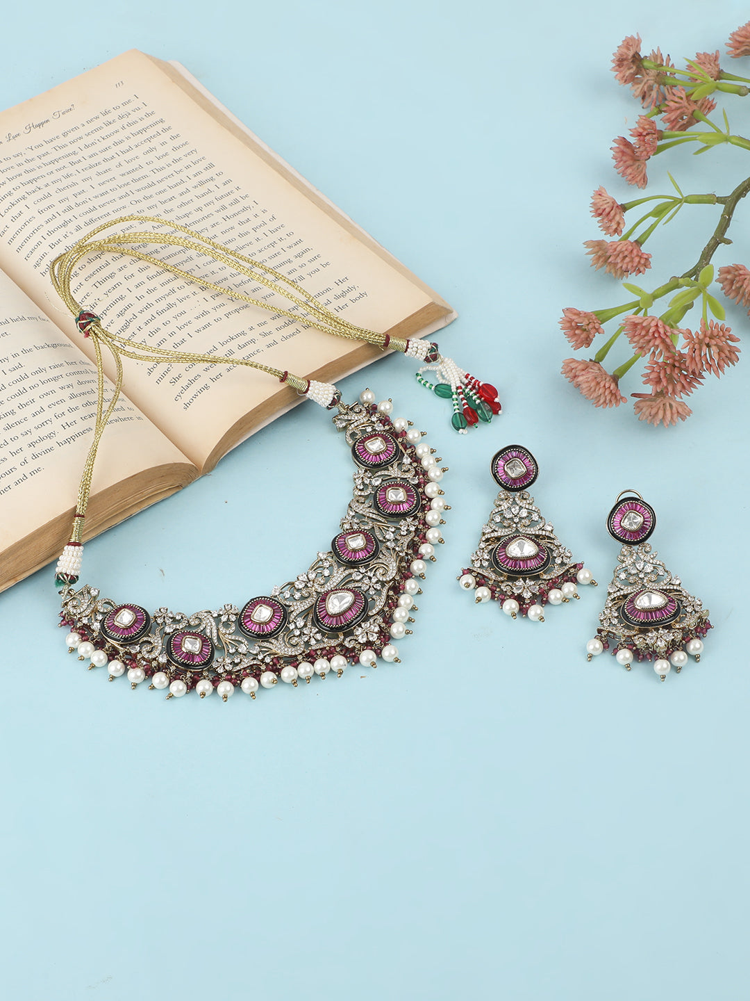 Gold-tone traditional necklace set with pink kundan-style stones, intricate detailing, pearl bead drops, and matching ornate dangling earrings.
