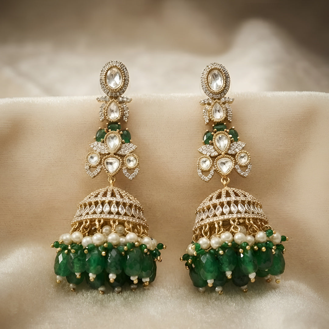 Luxury gold-plated Kundan jhumka earrings with sparkling CZ stones, emerald green bead drops, and pearl accents for women.
